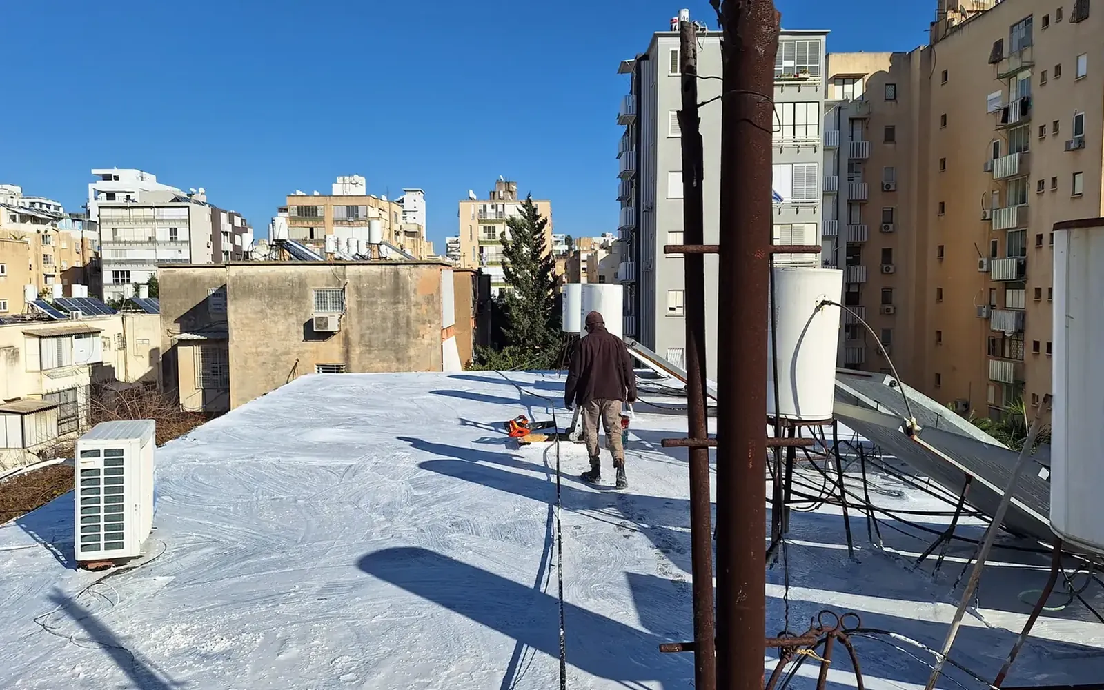 איש צוות בעבודה על גג בבניין מגורים בנתניה